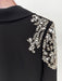 Black garment with intricate white embroidery on a plain background