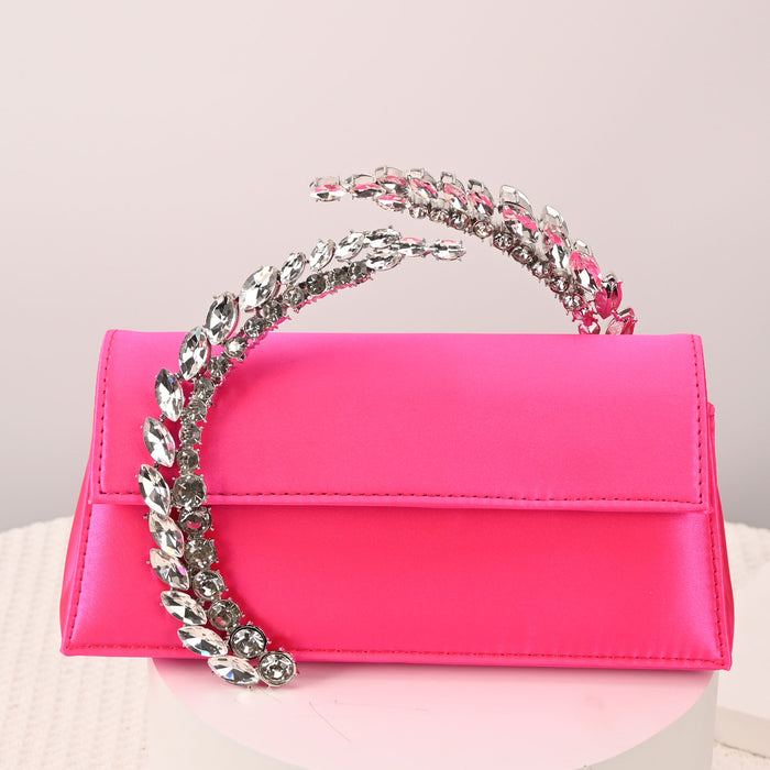 Pink handbag with a silver chain handle on a light pink background