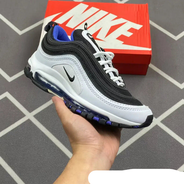 Black and white sneaker with blue accents held in front of a red Nike box on a tiled floor.