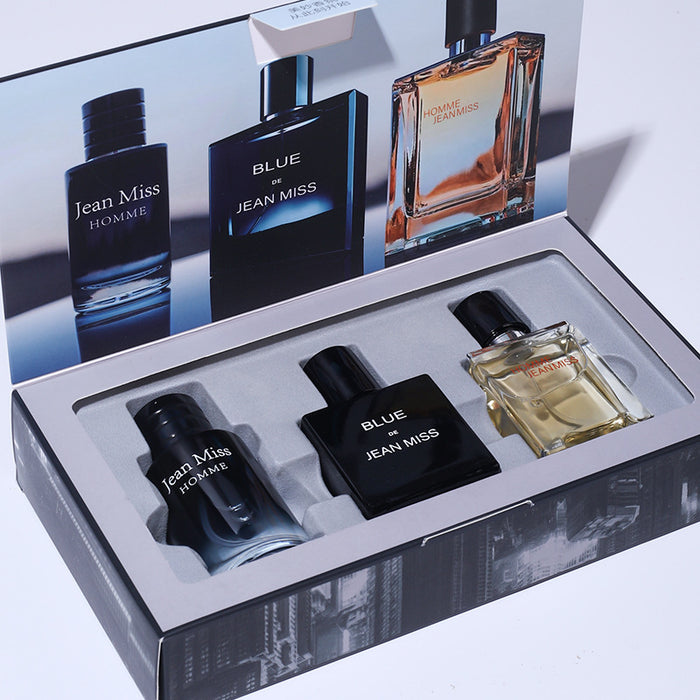 Set of Jean Miss perfume bottles in a display box with a promotional poster in the background.
