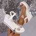 White wedge sandals with floral embellishments on a glittery background