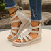 Beige wedge sandals with criss-cross straps worn with ripped jeans on a natural background.