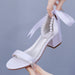 White high-heeled shoe with pearl embellishments on a gray background