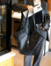 Person holding a large black handbag in an indoor setting