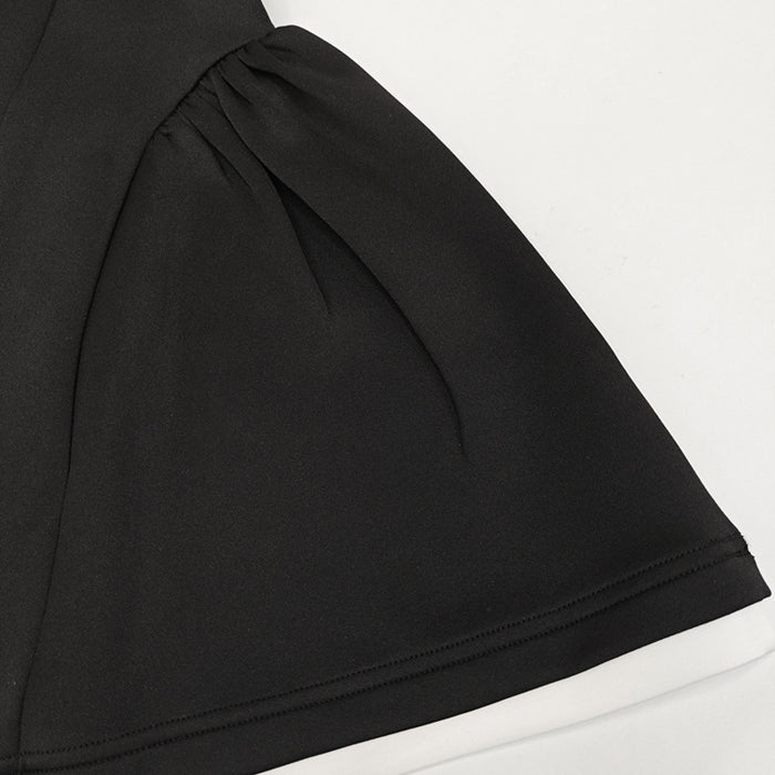 Close-up of a black garment with a white border on a light gray background