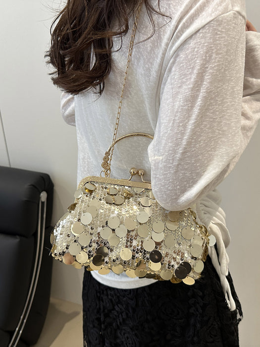 A woman wearing a white long-sleeve top and black skirt carries a small gold-tone handbag decorated with round metallic coin embellishments. The photo is taken from behind, showing the bag over her shoulder in an indoor setting.