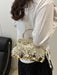 A woman wearing a white long-sleeve top and black skirt carries a small gold-tone handbag decorated with round metallic coin embellishments. The photo is taken from behind, showing the bag over her shoulder in an indoor setting.