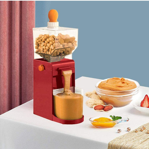 Red peanut butter maker with ingredients and a bowl of peanut butter on a white surface.