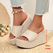 Beige wedge sandals worn with light blue jeans on a woven surface.