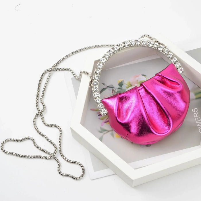 Pink metallic clutch with a chain on a white surface