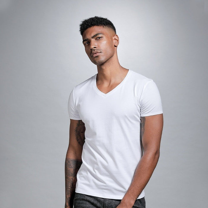 Man wearing a plain white t-shirt against a gray background