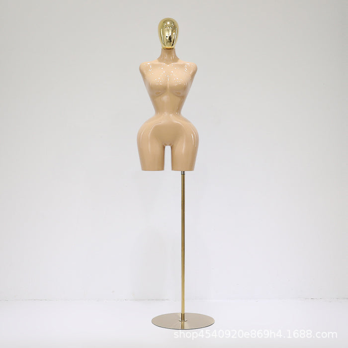 Mannequin torso on a stand with a gold head against a white background