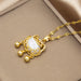 Gold pendant necklace with a white mother-of-pearl shell centerpiece, decorative filigree, and three dangling gold beads, displayed on a beige jewelry box.