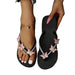 Black flip-flops with pink butterfly decorations on a white background