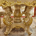 Gold ornate table in a luxurious room with red carpet and decorative elements.