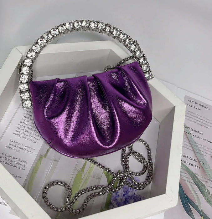 Purple handbag with a decorative handle on a white surface