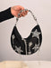 Black handbag with star-shaped embellishments held by a hand against a neutral background