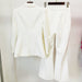 White suit jacket and pants on hangers against a white background