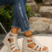 Beige sandals worn with ripped blue jeans against a natural background