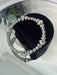 Silver beaded bracelet on a black heart-shaped box with a reflective surface background