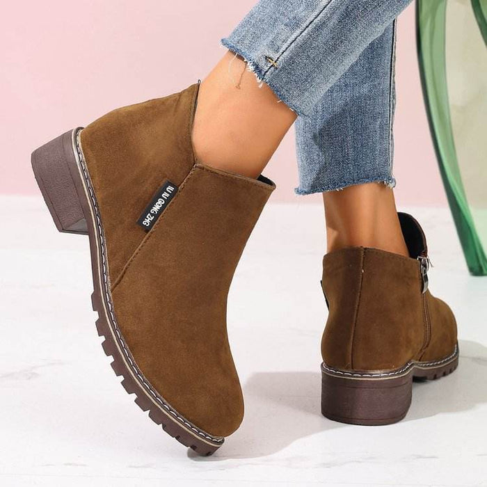 Brown ankle boots worn with blue jeans on a light background