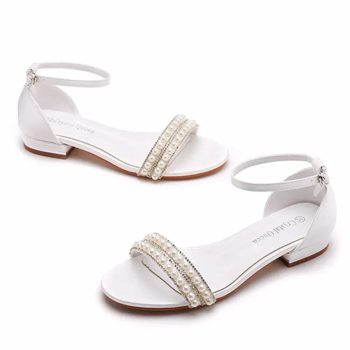 White sandals with pearl embellishments on a white background