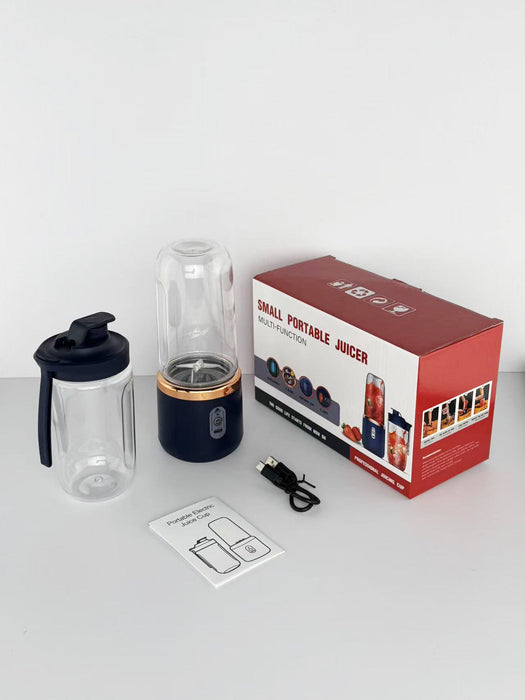 Small portable juicer with packaging, user manual, and USB cable on a white surface.