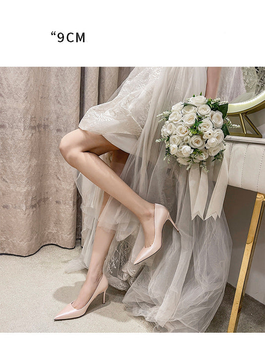 Woman in a white dress with high heels holding a bouquet, standing on a carpeted floor.