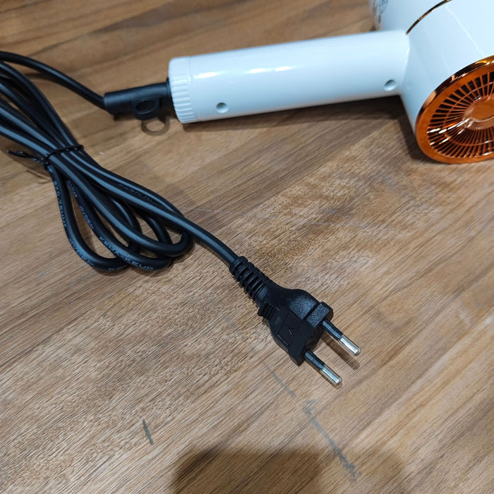White hair dryer with black cord on a wooden surface