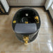 Black and gold sink with gray seat on a tiled floor