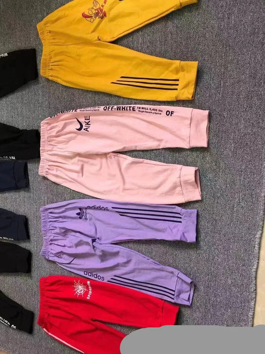 Set of colorful tracksuits with brand logos on a gray surface