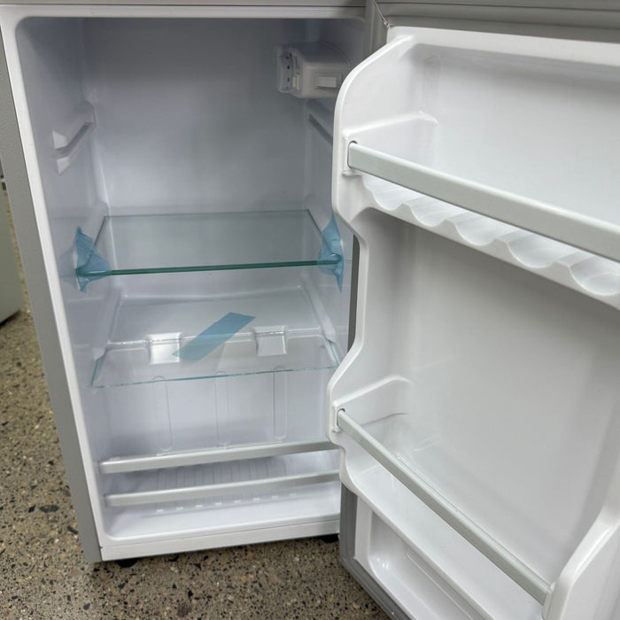Empty white refrigerator with open door on a speckled countertop