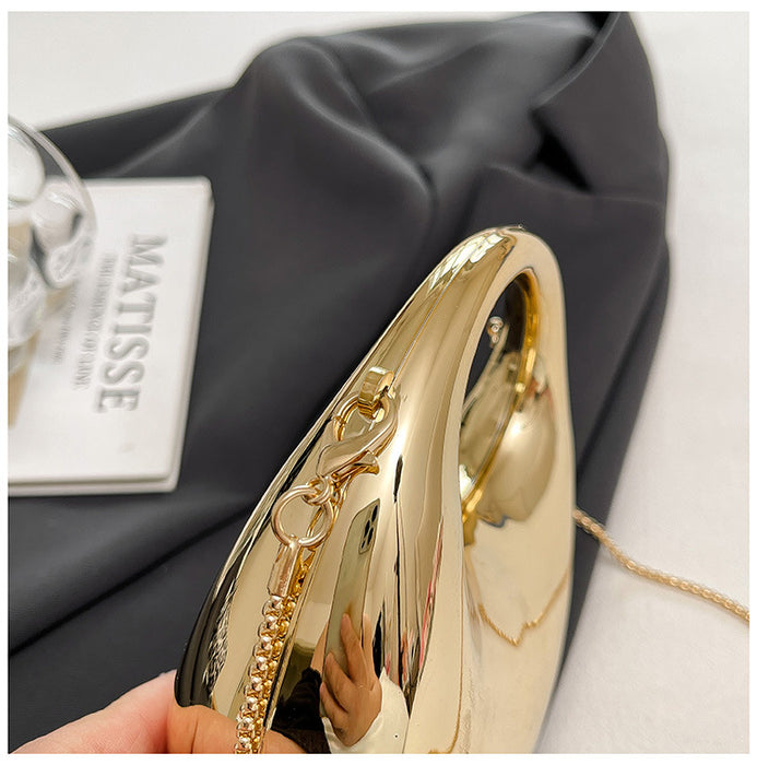 Gold handbag held by a hand on a gray fabric background