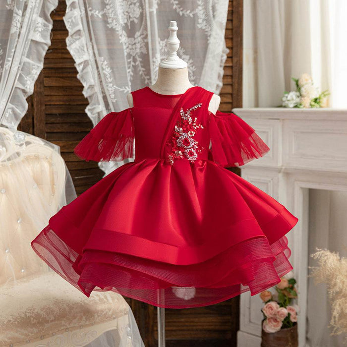 Red dress with floral embroidery on a mannequin against a decorative background