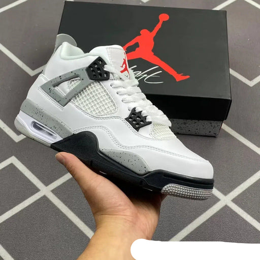 White sneaker with black and gray accents held by a hand, Jordan box in the background