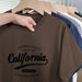 Brown t-shirt with 'California' text on a hanger with other shirts in the background