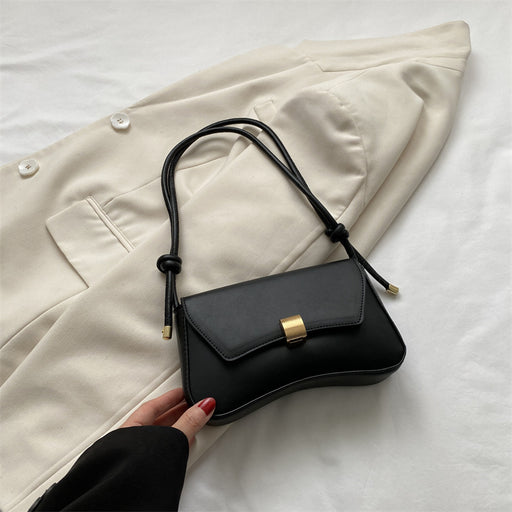 Black handbag with gold clasp on a beige coat