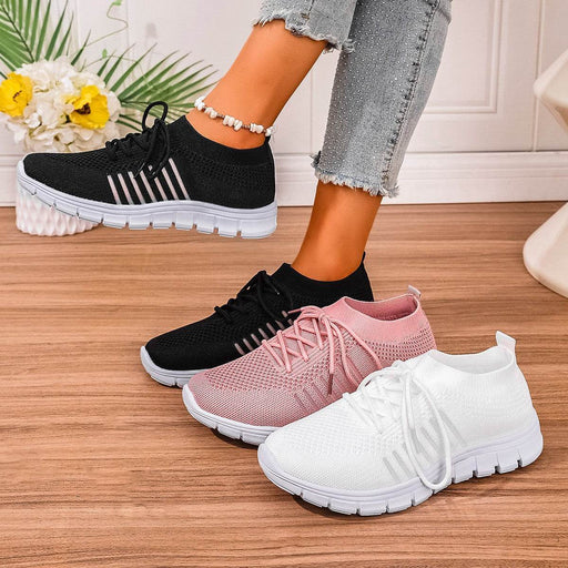 Black, pink, and white sneakers on a wooden floor with a blurred background.