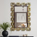 Decorative wall mirror with geometric frame on a light gray wall.