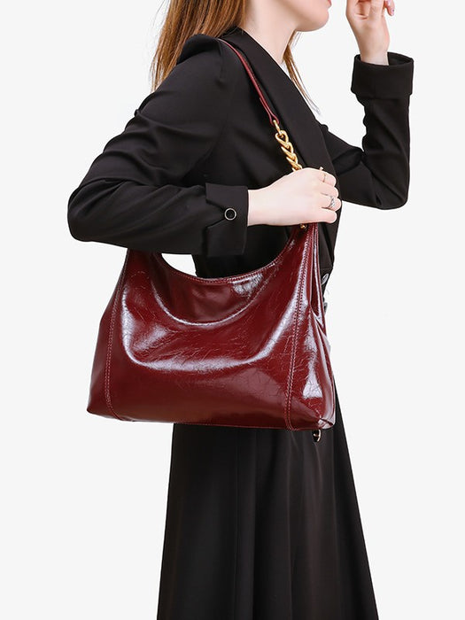 Person holding a red patent leather handbag against a white background