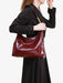 Person holding a red patent leather handbag against a white background