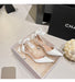White high-heeled shoes with decorative elements in a box, branded 'Chanel'.