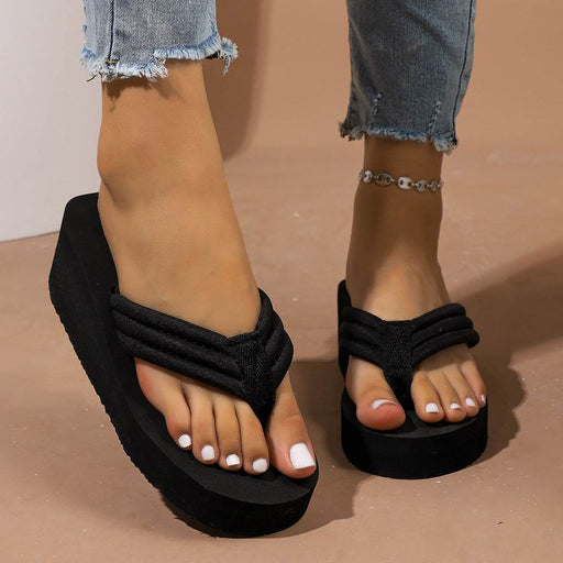 Black sandals worn with rolled-up jeans on a beige background