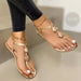Gold sandals worn with black pants on a neutral background
