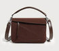 Brown handbag with a strap on a light gray background
