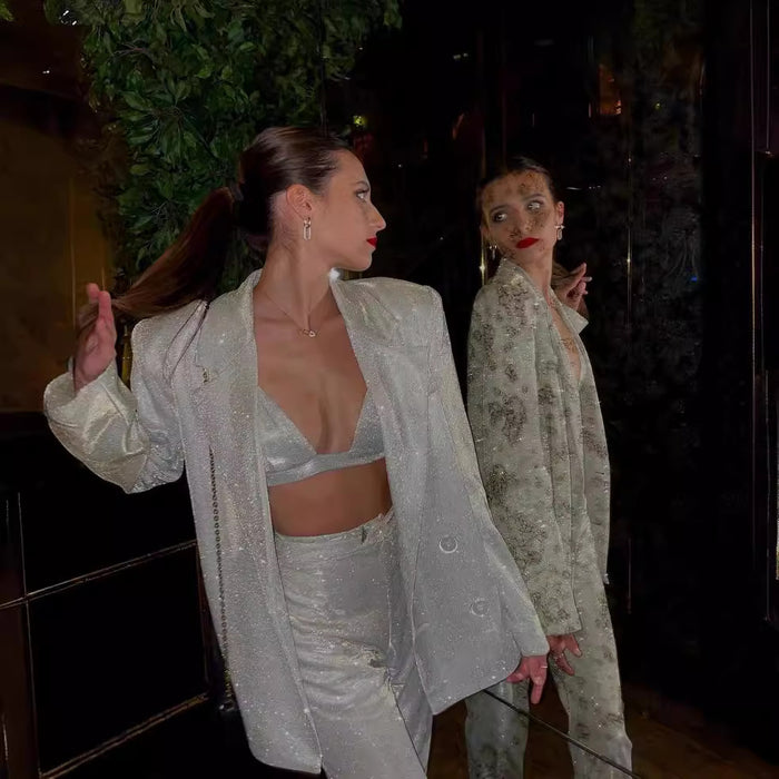 Woman in a silver outfit standing in front of a mirror.