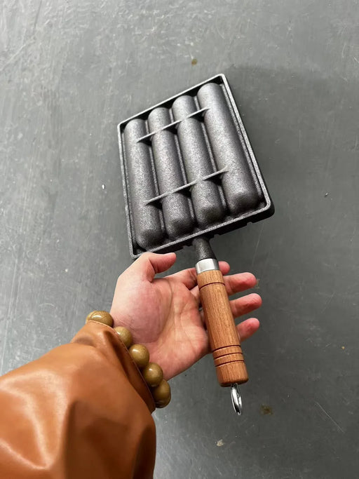 Hand holding a metal tool with wooden handle against a gray background