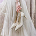Pair of sparkly high-heeled shoes held by a hand against a light background