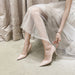 Person wearing beige high-heeled shoes with a light background