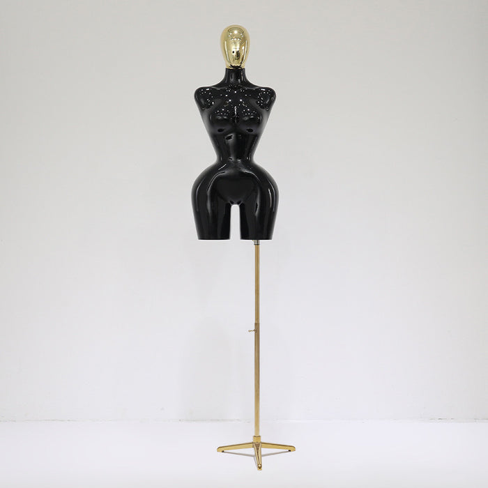 Black mannequin torso on a gold stand against a white background